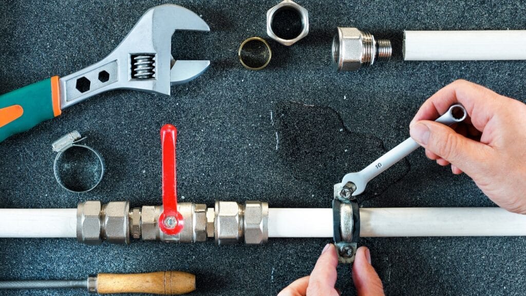 Plumber repairing a pipe valve with an adjustable wrench in Plant City