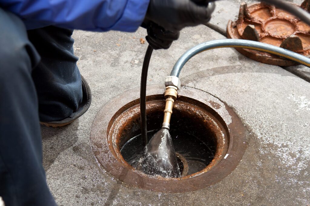 Plumber hydro jetting a sewer line through a manhole in Plant City
