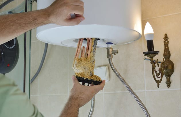 Technician removing mineral buildup from a water heater in Plant City