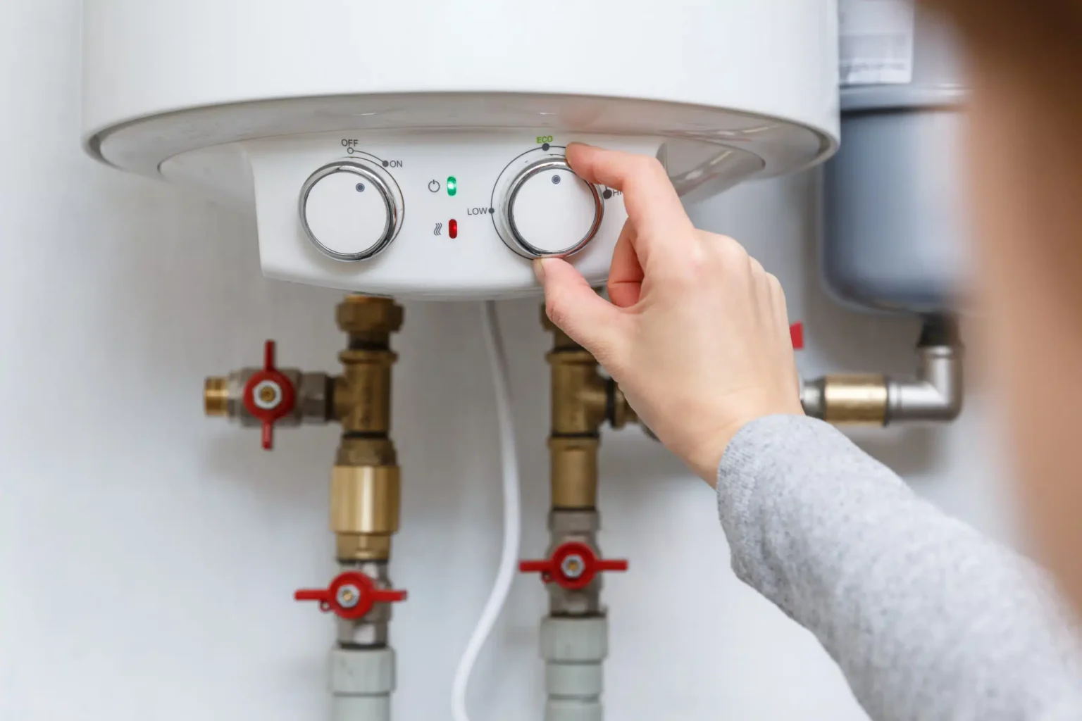 Homeowner adjusting the temperature controls on a water heater in Plant City